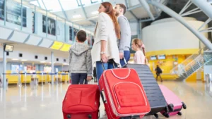 dois adultos, com seus dois filhos, segurando malas em um aeroporto, partindo para uma viagem com as crianças. uma grande viagem em família 