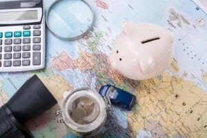 Artigos de viagem para economia em viagens, incluindo um cofrinho, uma calculadora, uma bússola, um binóculo e um mapa, simbolizando o planejamento financeiro de viagens.